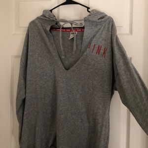 A low cut, gray, long sleeve shirt with a hood.